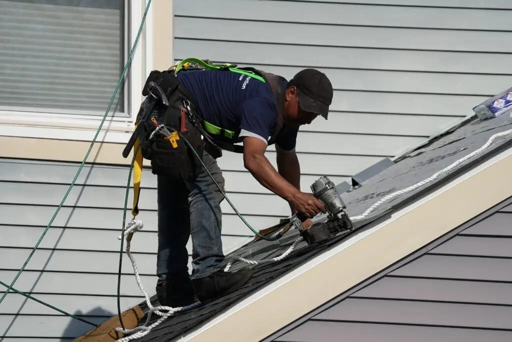Roofer with safety gear on steep roof